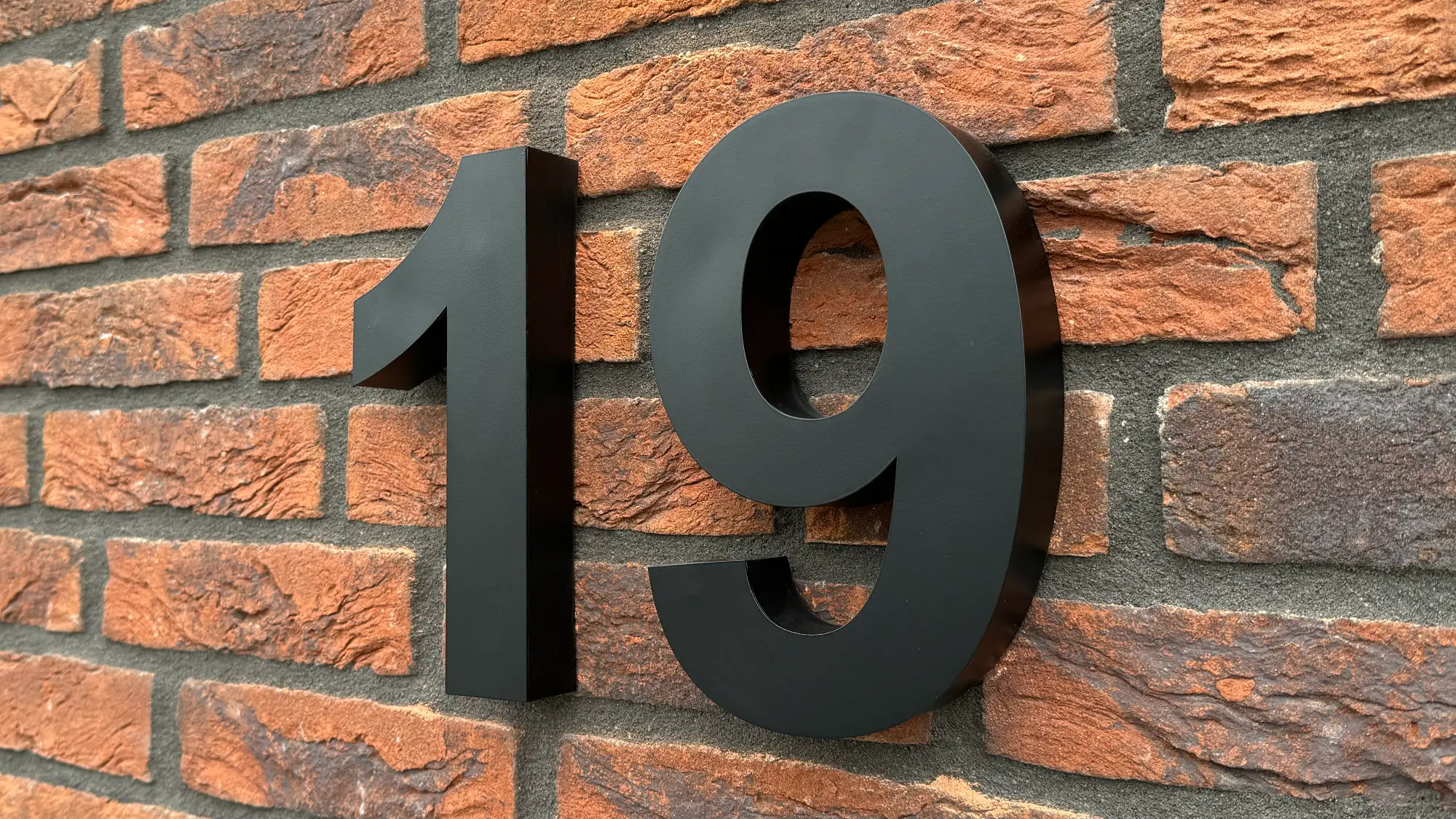 Lerop modern black 3D house number 20 cm in stainless steel, number 19 on a red brick facade